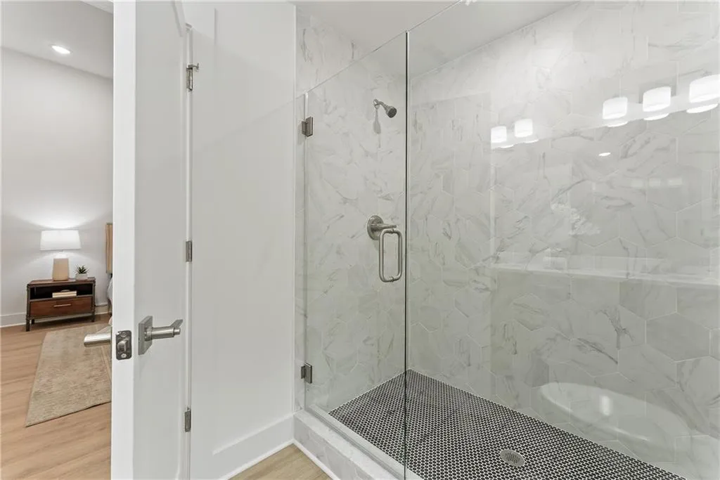 Full bath with a marble finish shower and wood finished floors