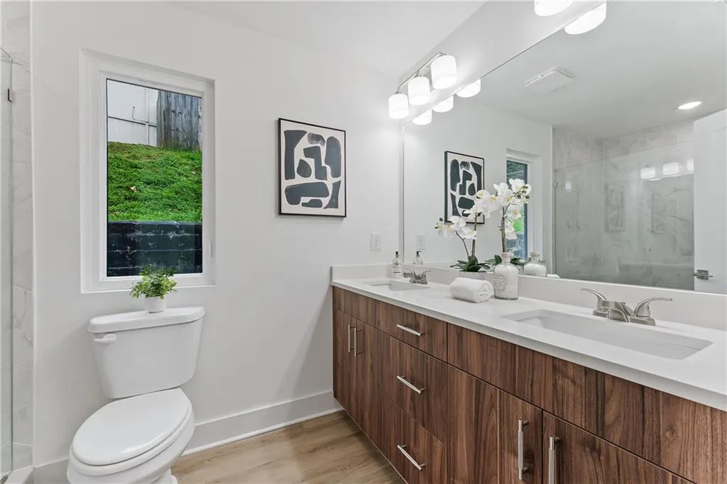 Bathroom featuring double vanity, wood finished floors, and a shower stall