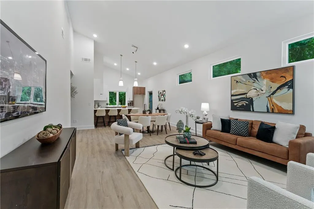 Living room with high vaulted ceiling, light wood-style flooring, and recessed lighting
