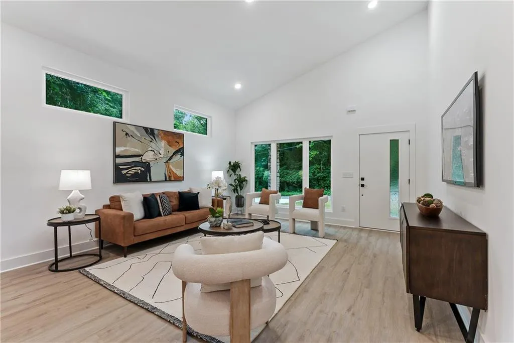 Living area with high vaulted ceiling, light wood-style floors, and recessed lighting