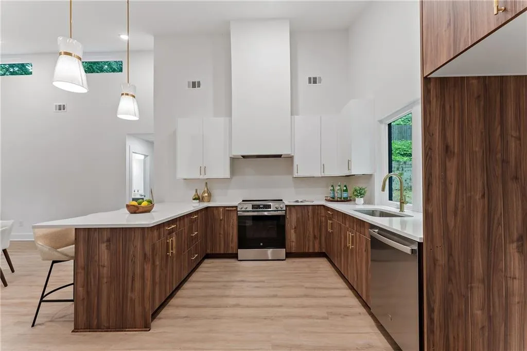 Kitchen with a peninsula, plenty of natural light, appliances with stainless steel finishes, a towering ceiling, and light countertops