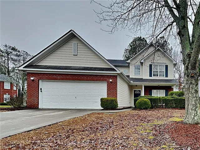 Traditional-style home featuring a two-car garage, brick facade detailing, and a covered entryway