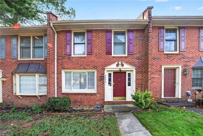 Brick exterior with white trim, arched portico, and bay window