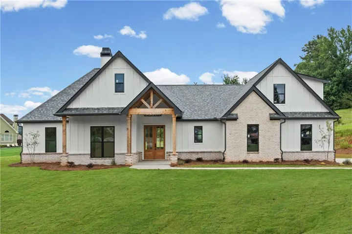 Modern farmhouse exterior featuring board and batten siding, light-toned brick accents, and a dark shingle roof