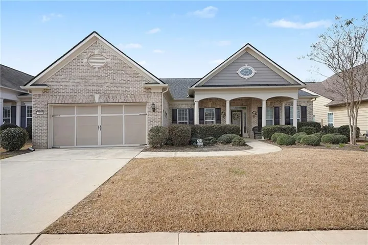 Brick exterior with an attached garage, covered front porch, and mature foundation plantings