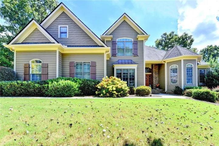 Craftsman-style exterior with gabled rooflines, stone accents, decorative window shutters, and a manicured lawn