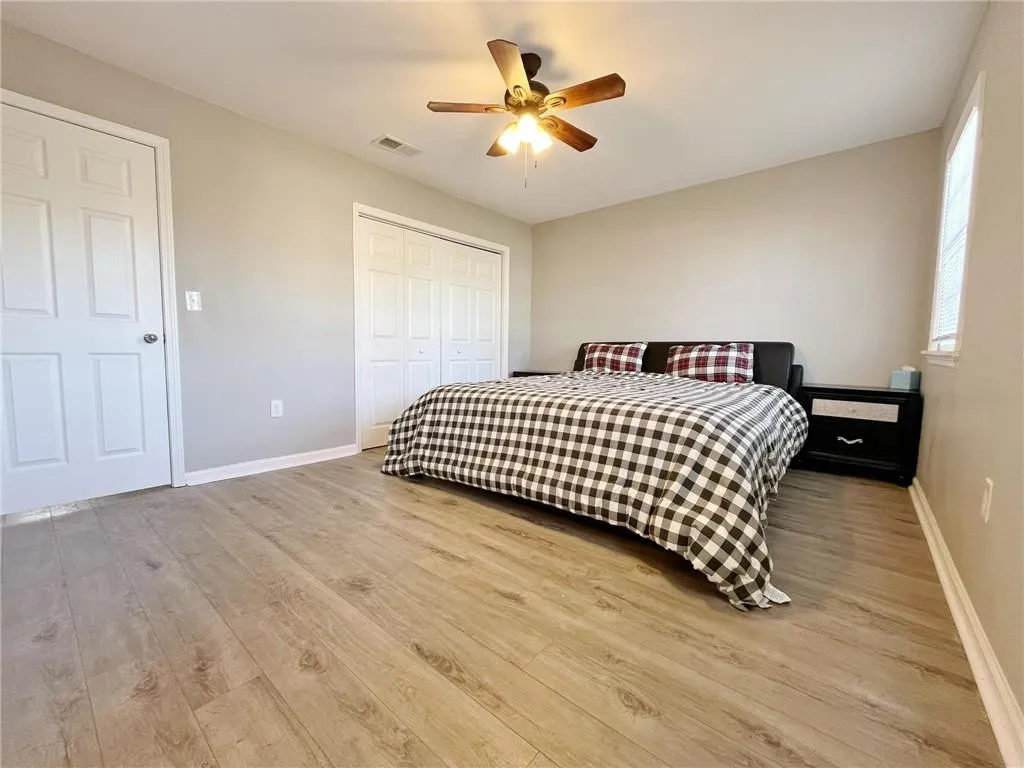 Bedroom with light wood-style floors, a closet, and a ceiling fan