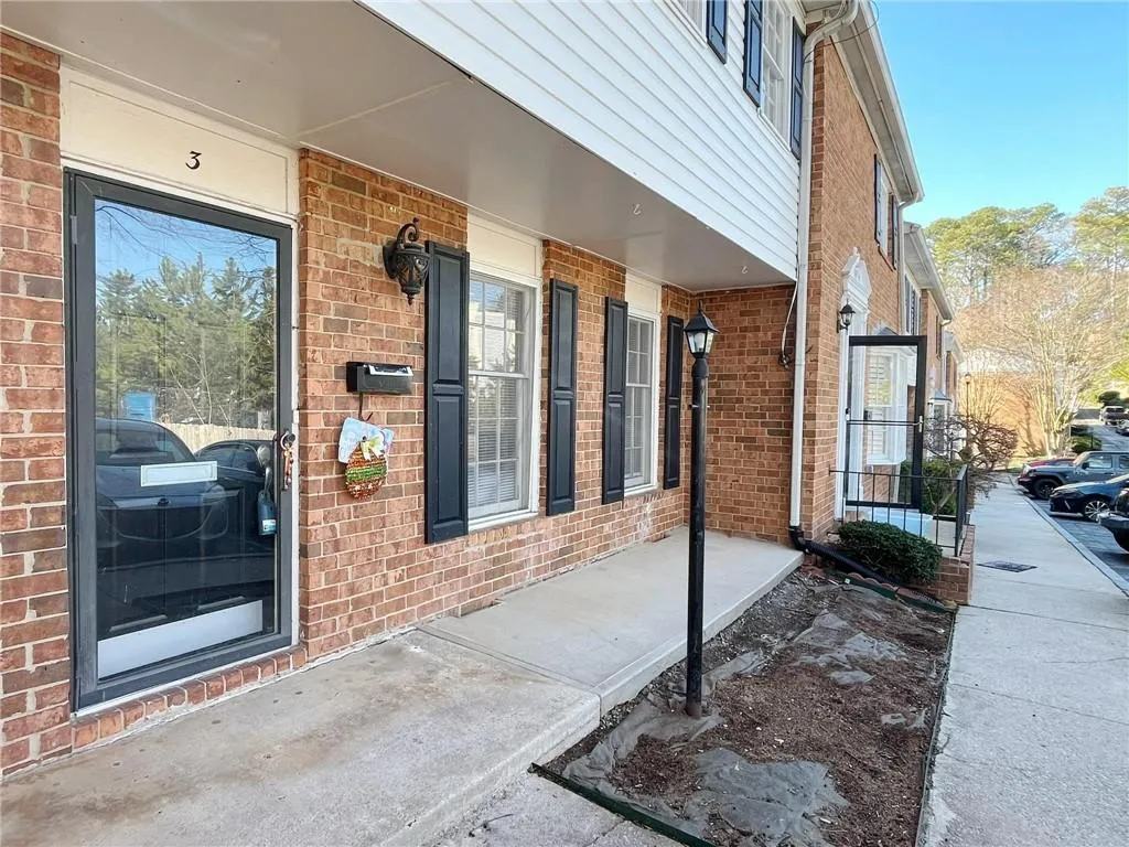 Doorway to property featuring a porch and brick siding