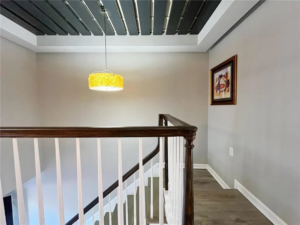 Corridor featuring dark wood-style flooring and an upstairs landing