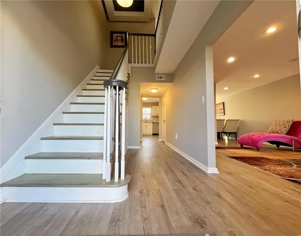 Stairway with wood finished floors, recessed lighting, and a high ceiling