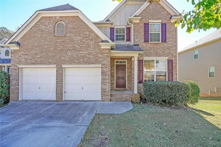 Brick exterior with accent shutters, two-car garage, and a covered entry