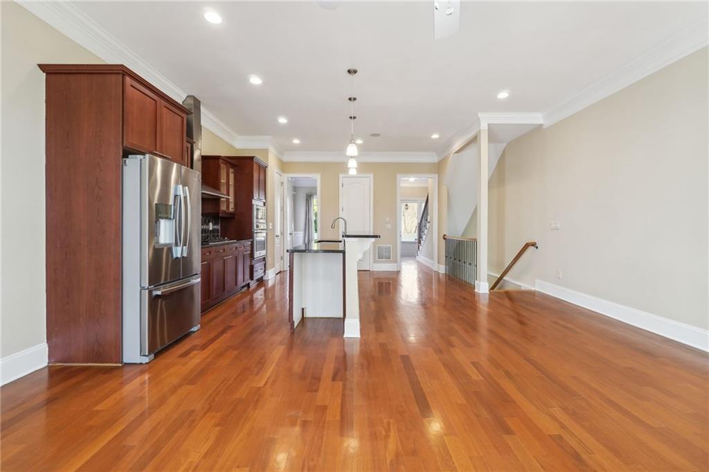 Kitchen featuring a center island with sink, appliances with stainless steel finishes, crown molding, a kitchen breakfast bar, and dark hardwood / wood-style floors
