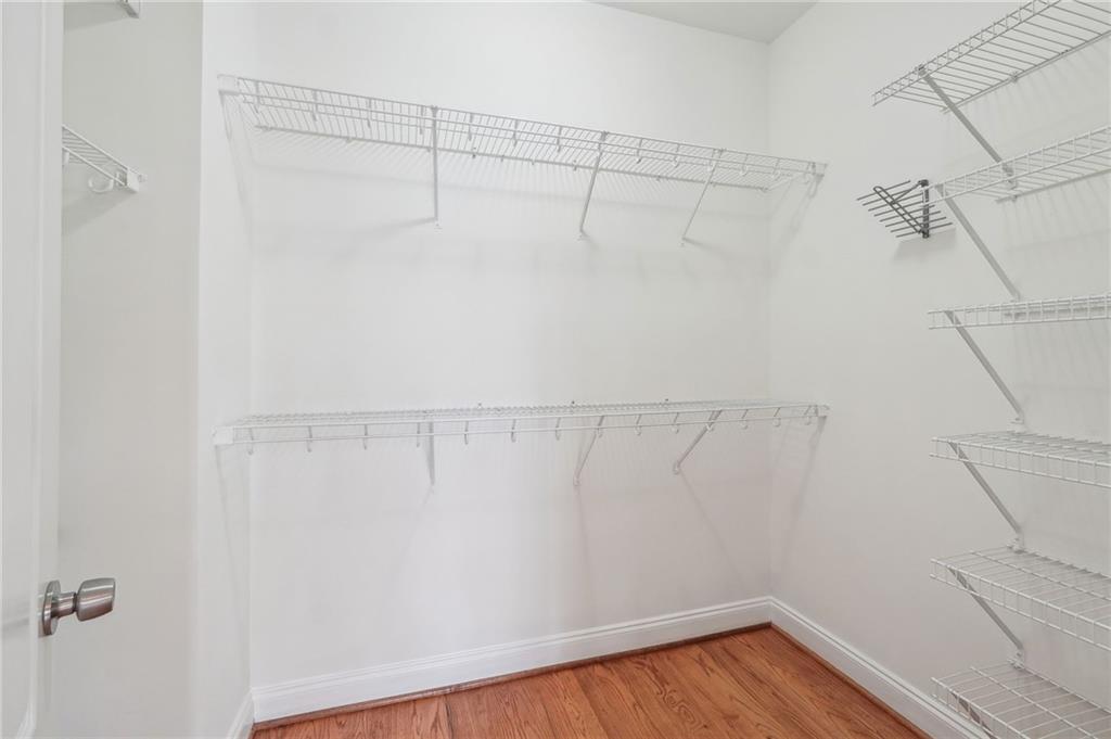 Walk in closet with light hardwood / wood-style flooring