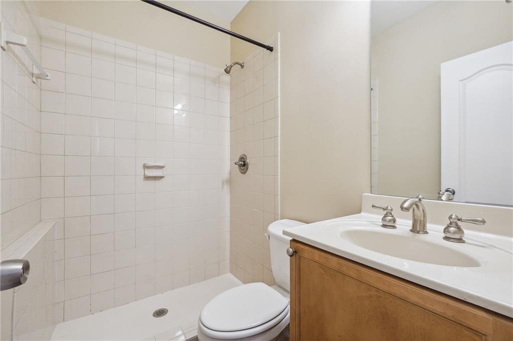 Bathroom featuring tiled shower, toilet, and vanity