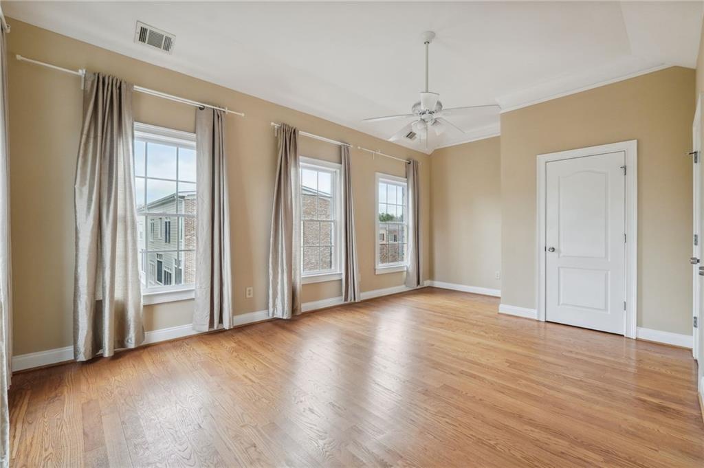 Spare room featuring light wood-type flooring, ceiling fan, and ornamental molding