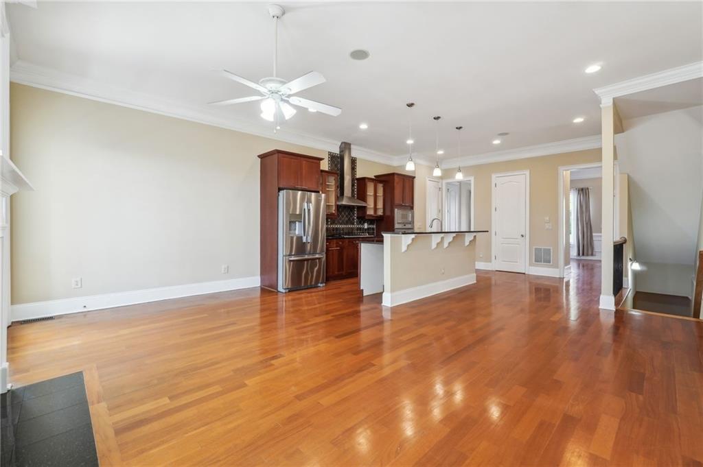 Unfurnished living room featuring light hardwood / wood-style flooring, crown molding, ceiling fan, and sink