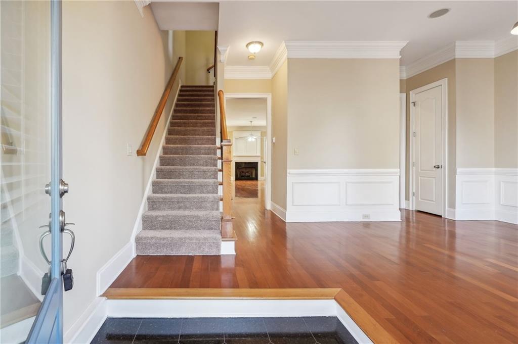 Stairway with hardwood / wood-style floors and ornamental molding
