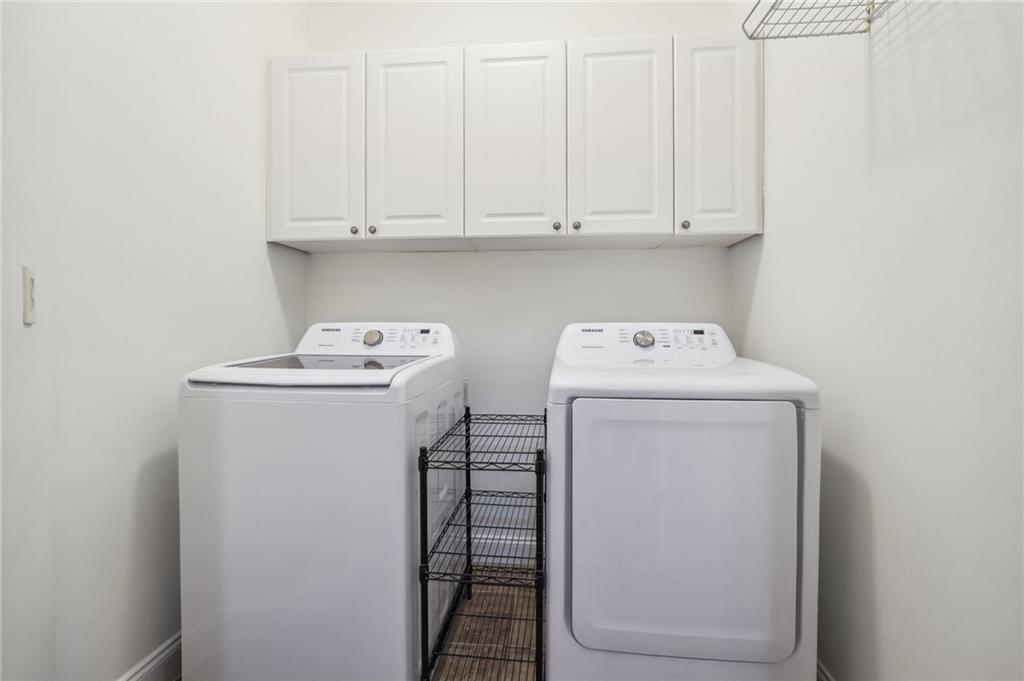 Laundry room featuring washing machine and clothes dryer and cabinets