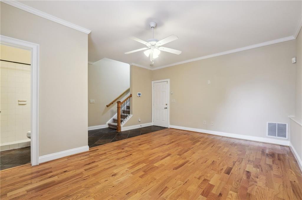 Unfurnished living room featuring crown molding, ceiling fan, and hardwood / wood-style flooring