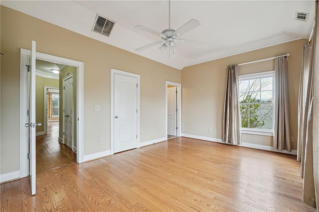Unfurnished bedroom with light hardwood / wood-style flooring, ceiling fan, ornamental molding, and lofted ceiling