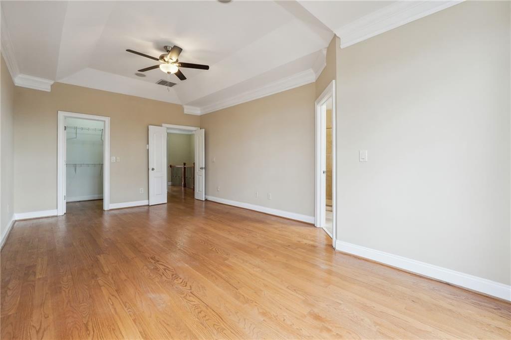 Spare room featuring a raised ceiling, light hardwood / wood-style flooring, crown molding, and ceiling fan