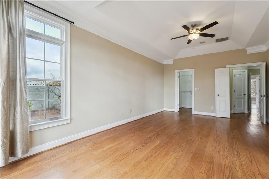 Spare room with a wealth of natural light, ornamental molding, ceiling fan, and hardwood / wood-style floors