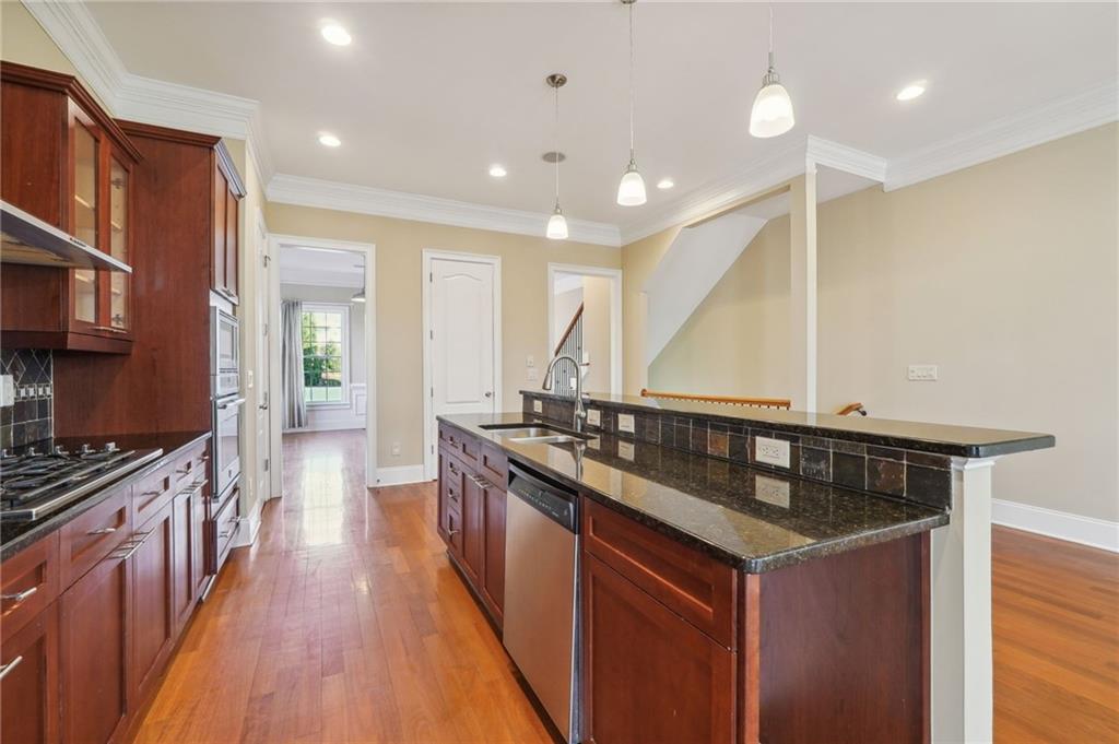 Kitchen featuring stainless steel appliances, light hardwood / wood-style flooring, sink, and an island with sink