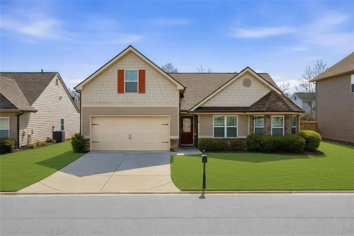 Craftsman-style exterior featuring a covered front entry, attached two-car garage, brick accents, and a front yard with established landscaping