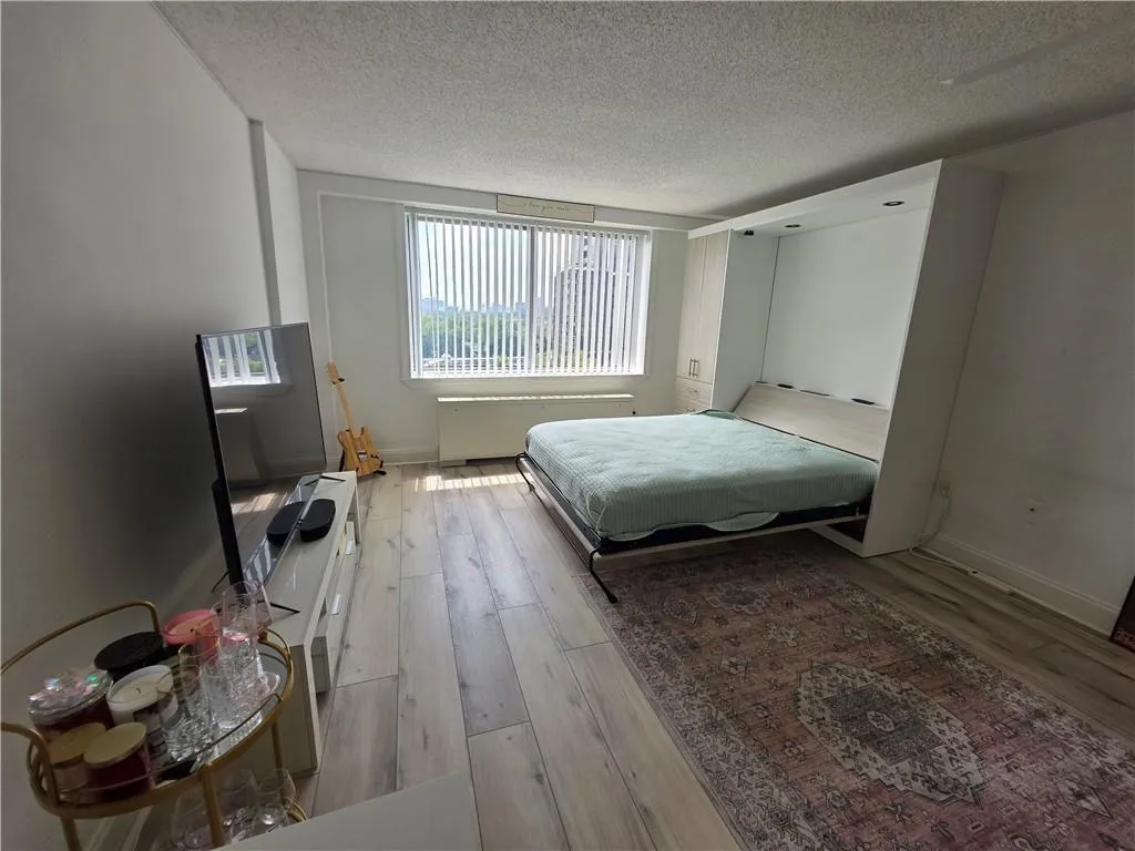 Bedroom featuring a textured ceiling, light wood-style flooring, and radiator