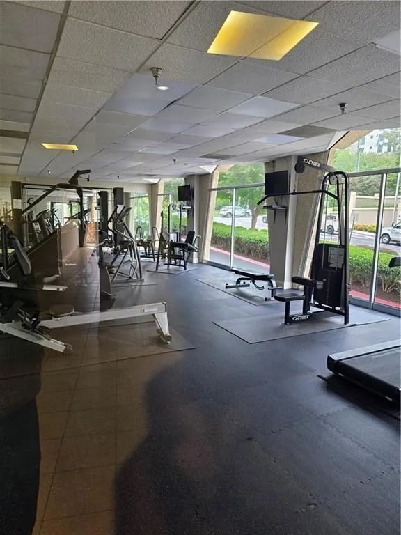 Workout area featuring a paneled ceiling and a wall of windows