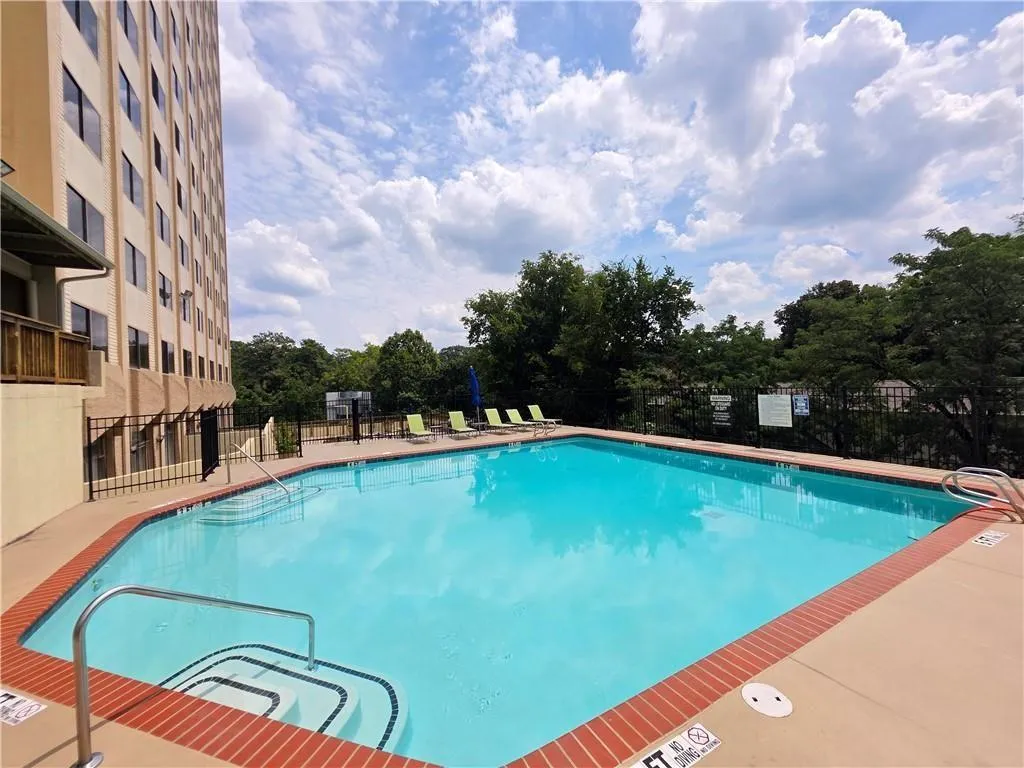 Community pool with a patio and view of scattered trees