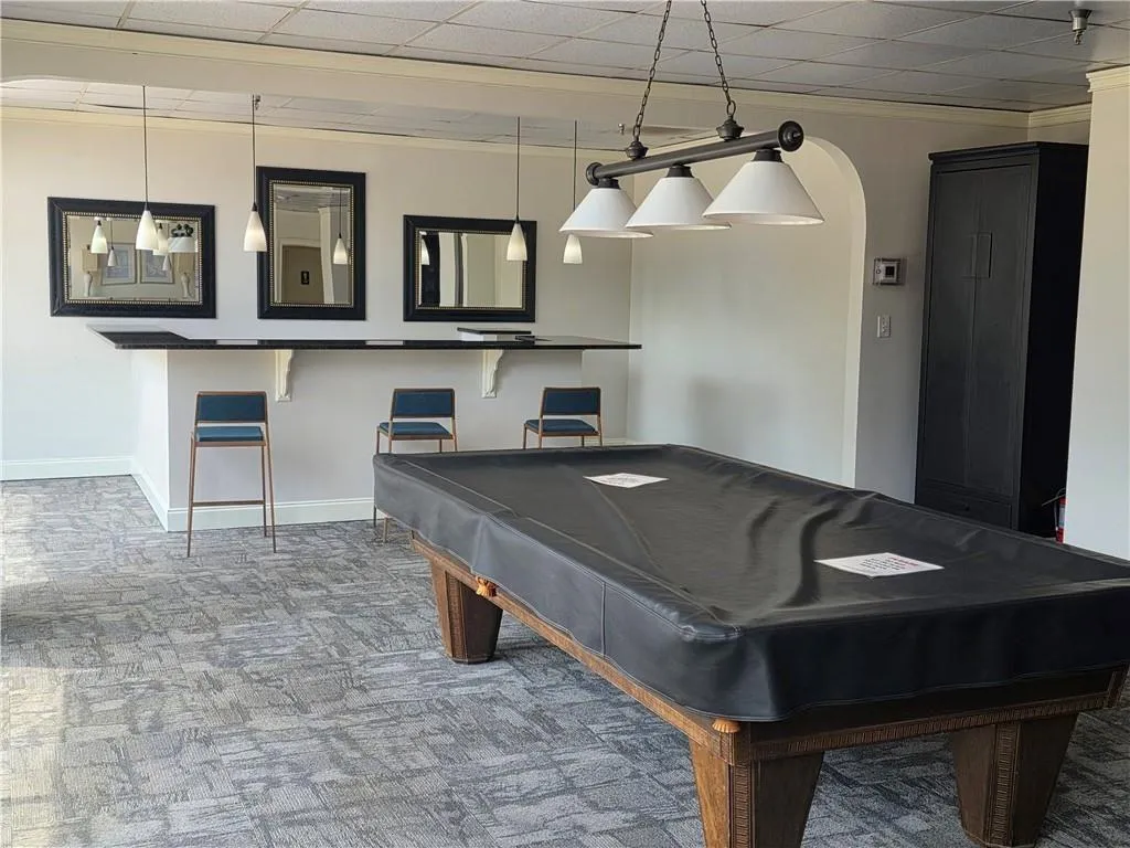 Game room with billiards, arched walkways, a drop ceiling, light carpet, and crown molding