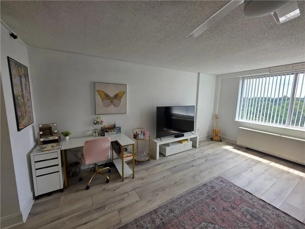 Home office featuring light wood-style floors and a textured ceiling