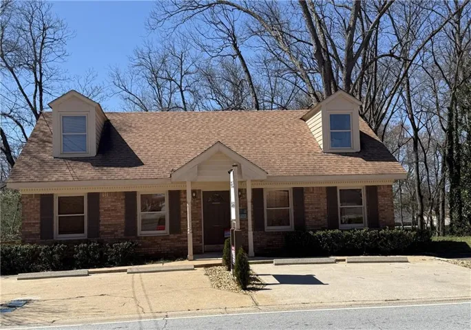 Brick exterior with dormer windows, brown shingle roof, and a covered entry