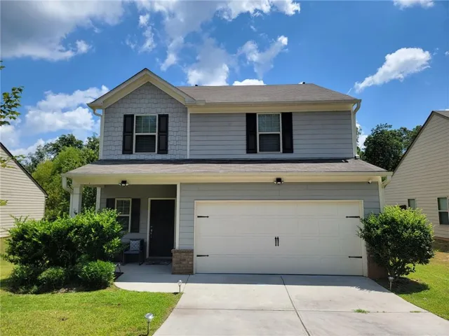 Two-story residence featuring light gray siding, a covered front porch, an attached garage, and a concrete driveway