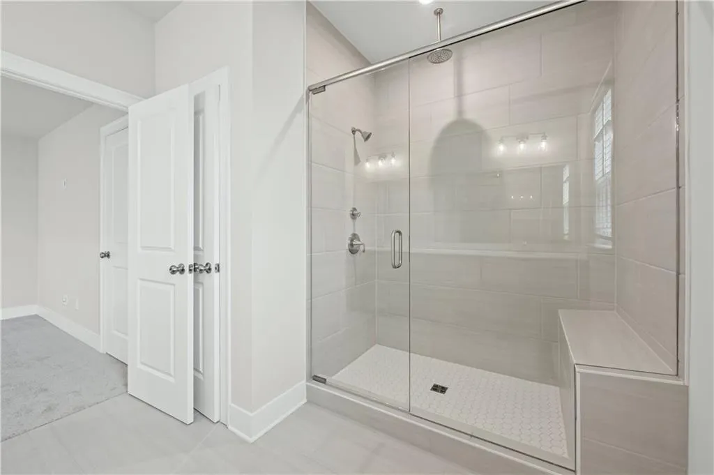Primary bathroom with oversized, frameless glass shower, with both wall mount and rainshower fixtures and built-in bench seat