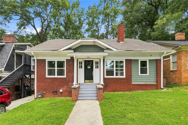 Brick-clad facade featuring a covered entry, white column supports, and a shingle roof