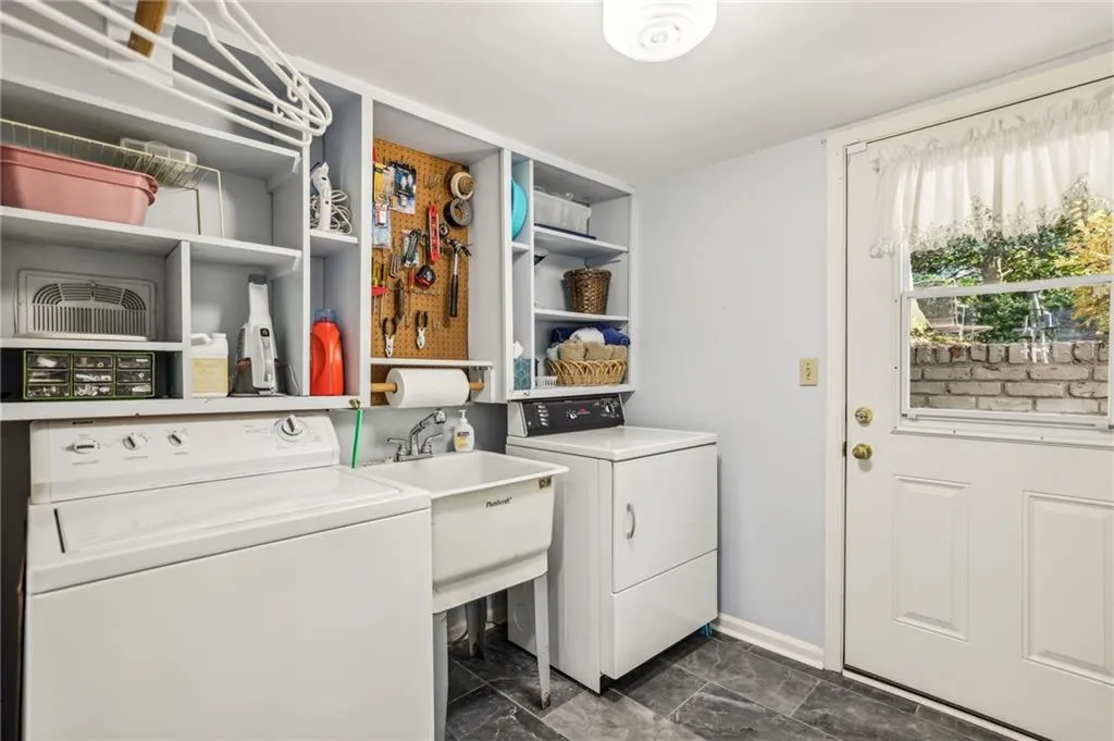 Kaundry room with built-in shelves, laundry sink, laundry chute from primary bath, and exterior entry to yard and the basement area