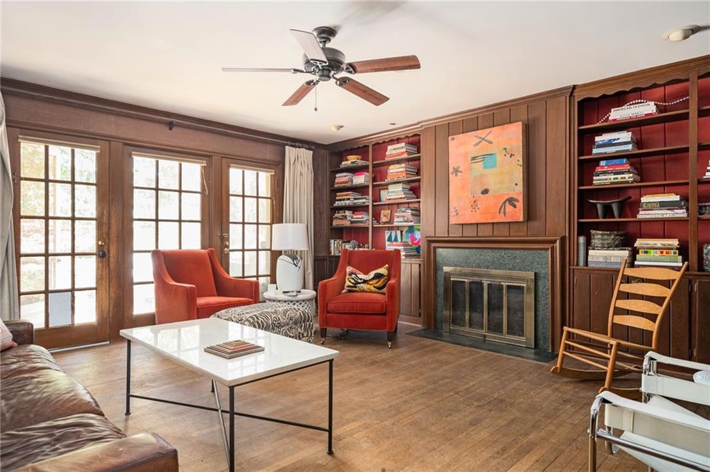 Den featuring  built in shelves, and hardwood / wood-style floors
