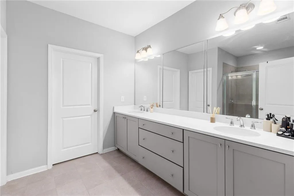Full bath with a stall shower, double vanity, and light tile patterned floors