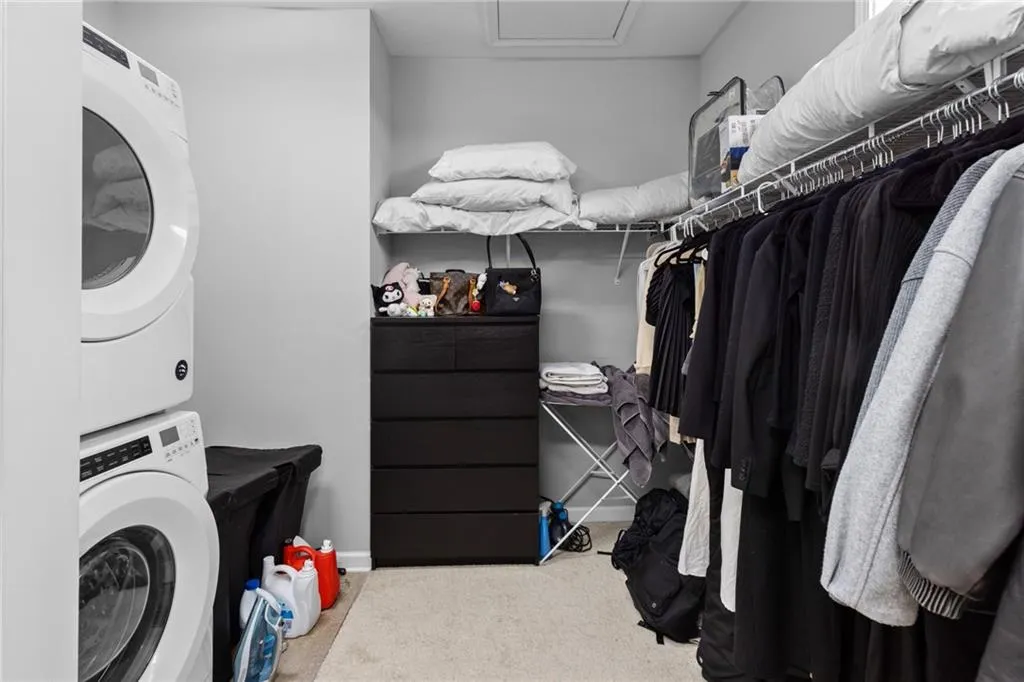 Spacious closet featuring stacked washer / drying machine and light carpet