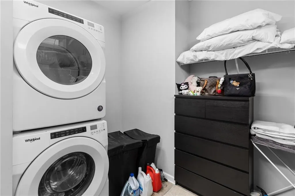 Laundry room with stacked washer and clothes dryer and baseboards