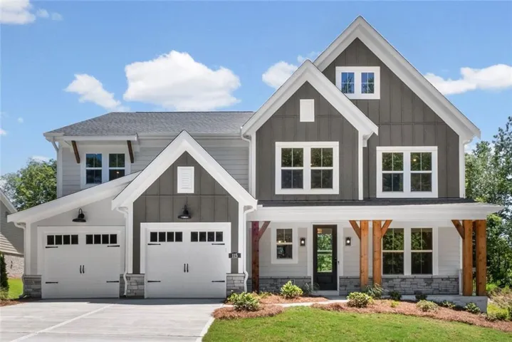 Modern farmhouse exterior featuring mixed siding, a covered front porch with exposed wood beams, a two-car garage with carriage-style doors, and stone accents