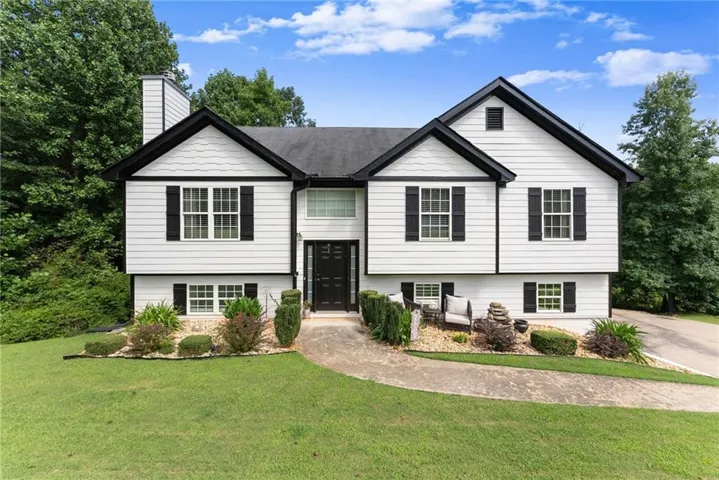 Split-level residence featuring white siding and black trim accents