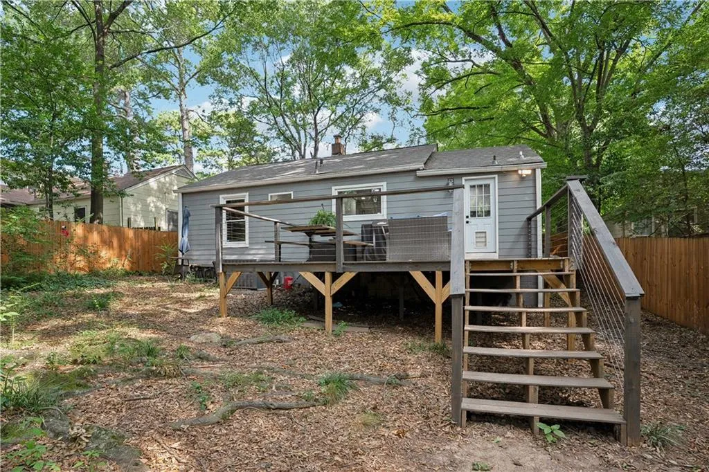 Rear view of property featuring stairway, a deck, a chimney, and roof with shingles