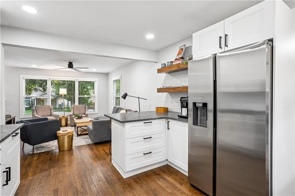 Kitchen with stainless steel refrigerator with ice dispenser, open floor plan, open shelves, a peninsula, and white cabinetry