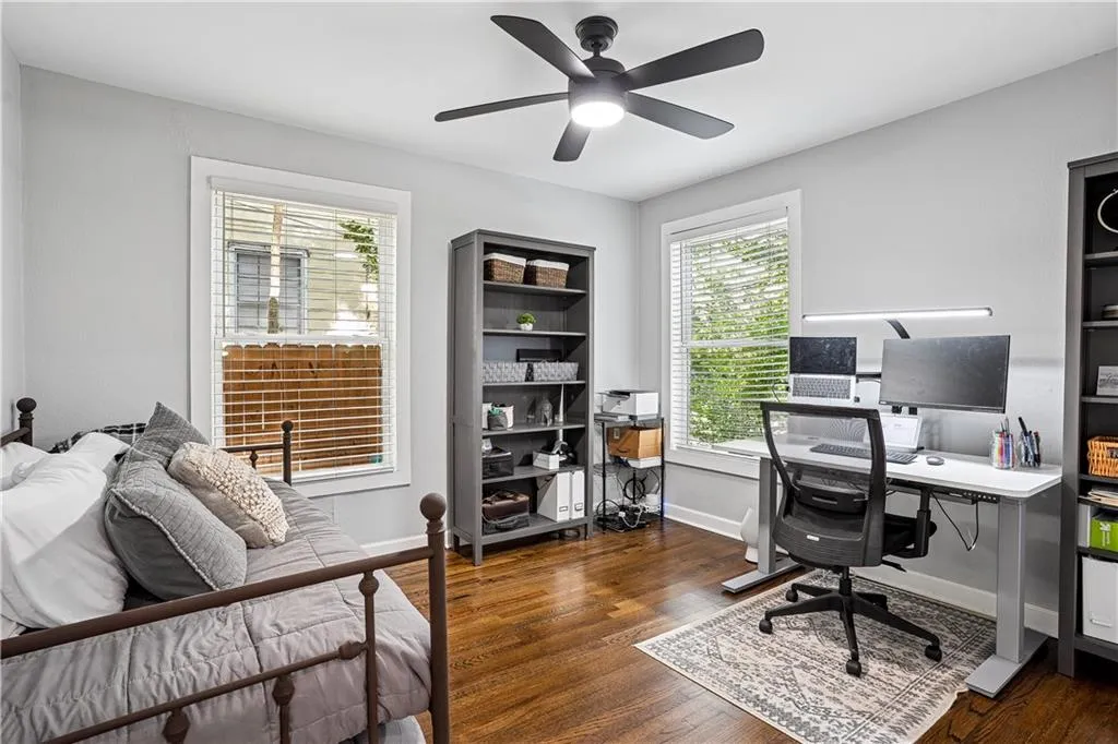 Office space featuring dark wood-style flooring, healthy amount of natural light, and a ceiling fan