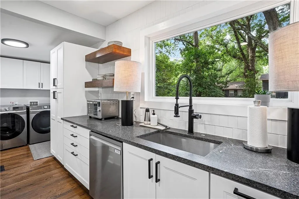 Kitchen featuring plenty of natural light, white cabinets, stainless steel dishwasher, and separate washer and dryer