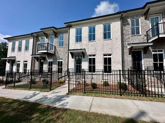 Brick exterior featuring individual balconies, prominent window placement, and decorative awnings