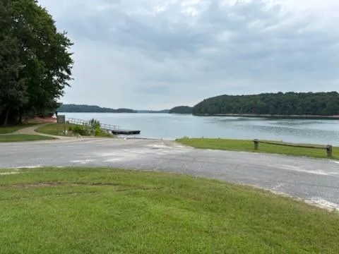 Waterfront access with boat ramp, adjacent dock structure, and natural shoreline